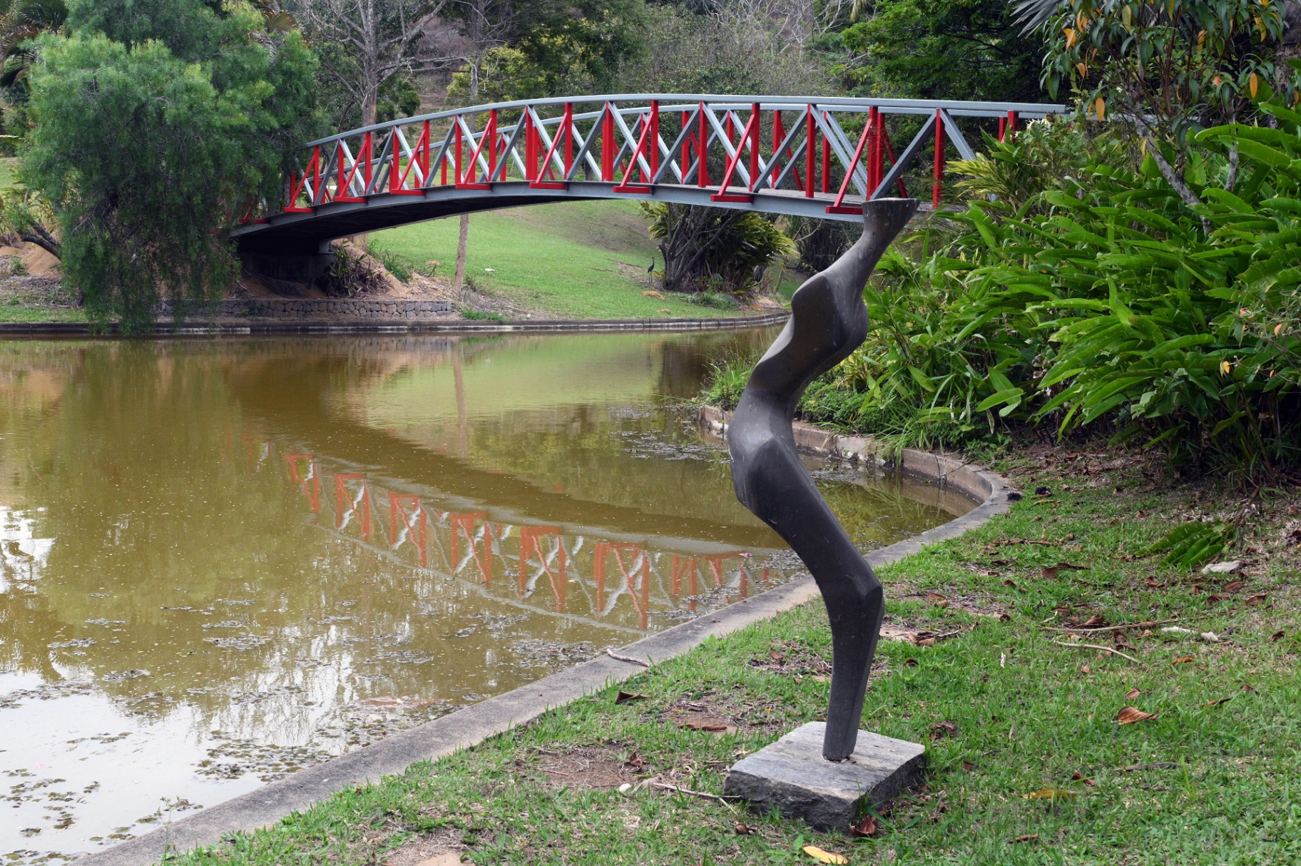 Escultura em jardim com ponte vermelha ao fundo