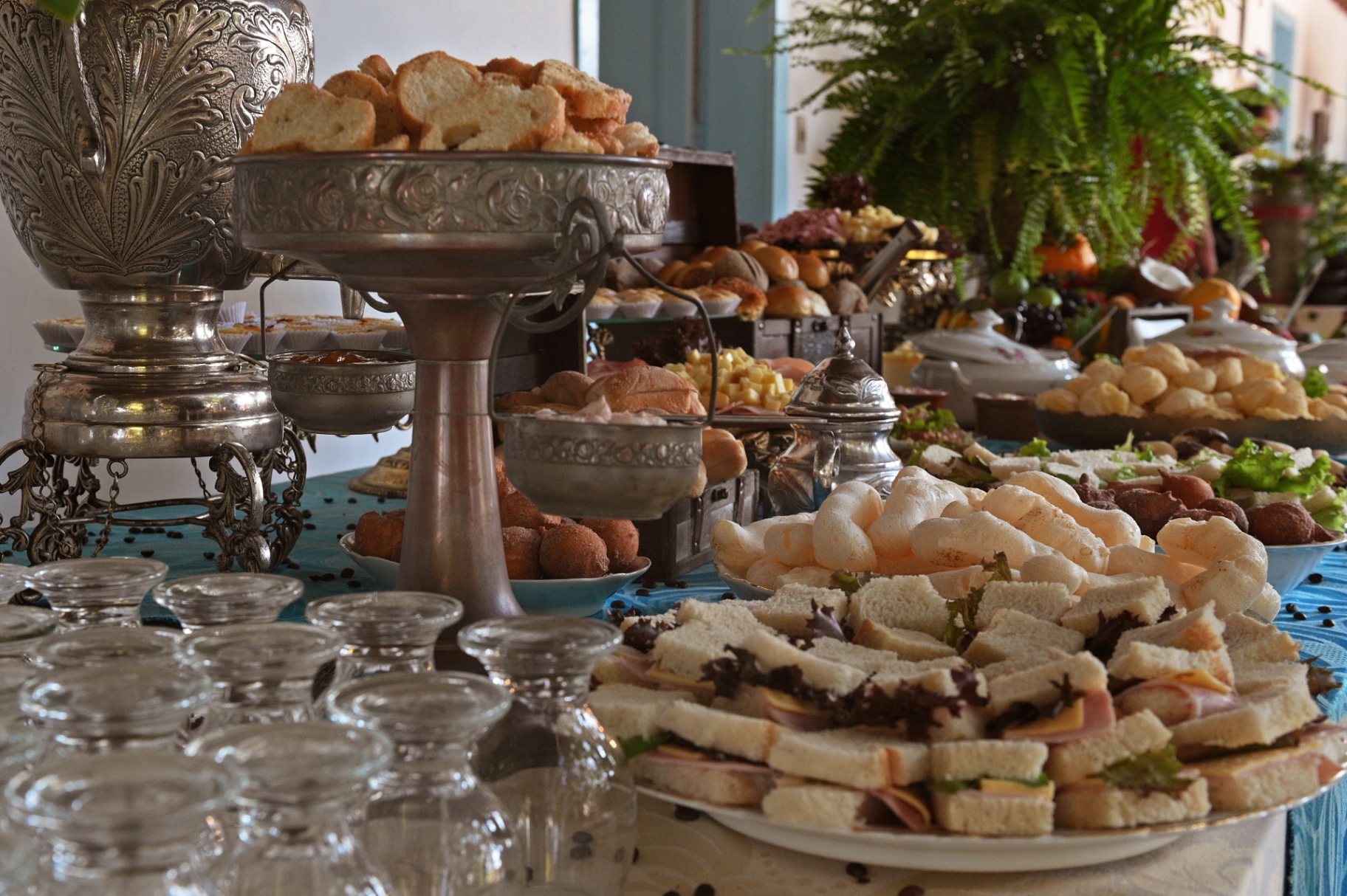 Mesa de café colonial com pães, doces e prataria